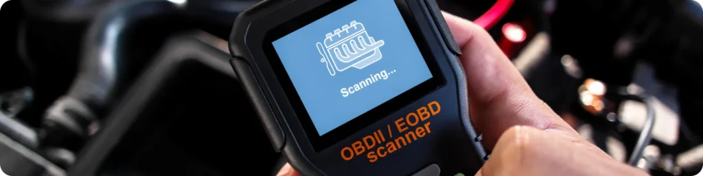 A close-up of a hand holding an OBDII/EOBD scanner with a screen displaying a scanning progress graphic, next to a car engine. Engine Diagnostics & Repair, auto repair services in South Jordan UT