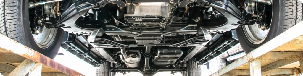 View of the underside of a vehicle showing the suspension, exhaust system, and other mechanical components while the car is elevated on a lift. preventative maintenance, auto repair services in South Jordan UT